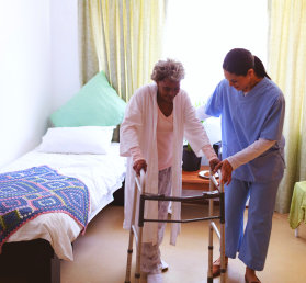 caregiver assisting an elderly woman using a walker