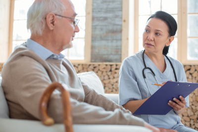 concentrated doctor holding clipboard while taking notes and communicating with senior man