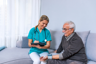 nurse measuring blood pressure of senior man at home