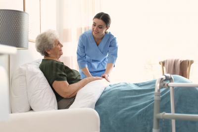 nurse assisting senior woman to bed