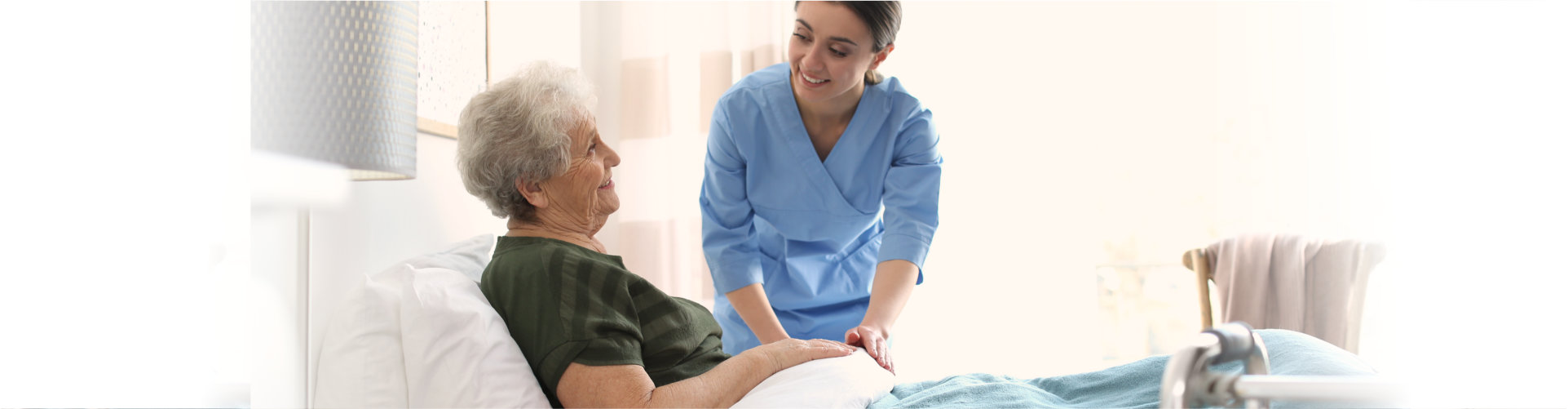 nurse assisting senior woman to bed